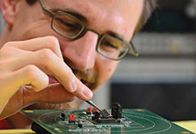 An ETH Zurich scientist uses tweezers to mount a PULP microprocessor on to a test 
board for measurement.